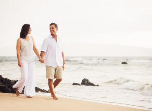 Couple enjoying an active beach vacation while avoiding summer travel fatigue through movement, hydration, and healthy travel habits.