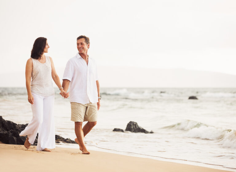 Couple enjoying an active beach vacation while avoiding summer travel fatigue through movement, hydration, and healthy travel habits.