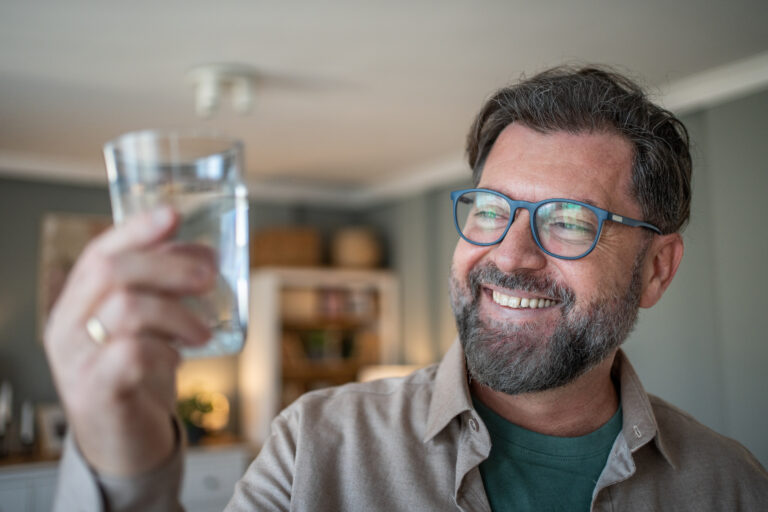 Man over 50 drinking water as part of healthy habits that may address causes of constipation.